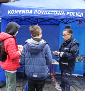 policjantka przekazuje uczestnikom festynu materiały promocyjne