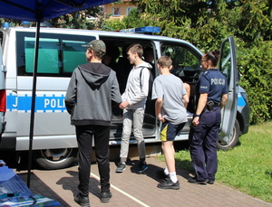 młodzież i policjanci przy stoisku policyjnym podczas dni otwartych na placu przed szkołą