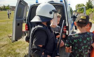 policjant pokazuje policyjny sprzęt i radiowóz podczas festynu