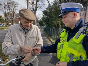 policjant przekazuje seniorowi zawieszkę odblaskową