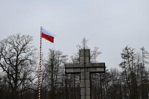 betonowy krzyż i flaga Polski