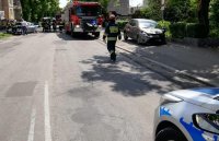 Uszkodzony samochód, radiowóz i wóz strażacki. Strażacy zabezpieczają miejsce.
