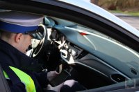 policjant siedzi w radiowozie, sprawdza dane kierowcy