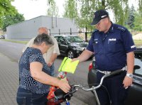policjant przekazuje kamizelkę odblaskową rowerzyście