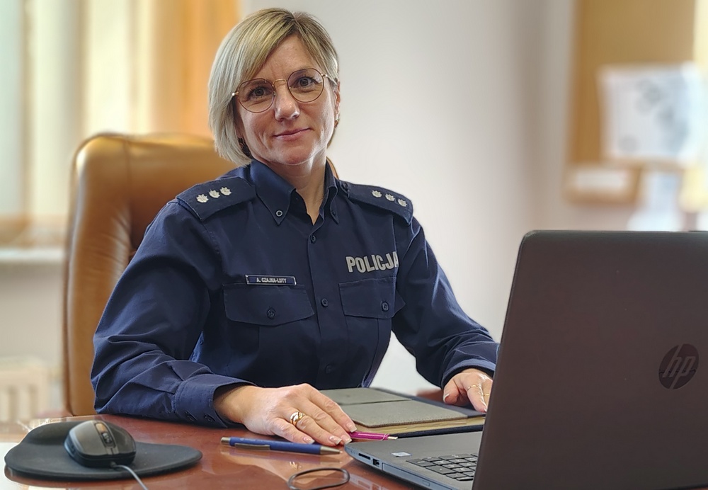 uśmiechnięta policjantka w mundure siedzi za biurkiem