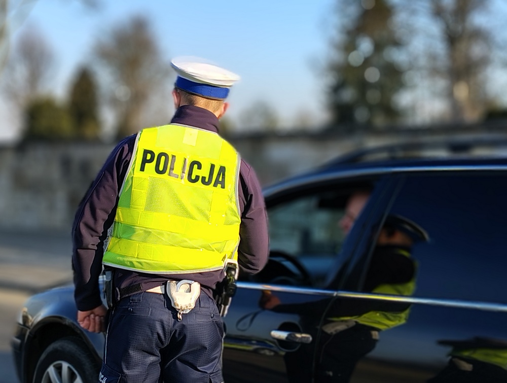 policjant w żółtej kamizelce kontroluje samochód