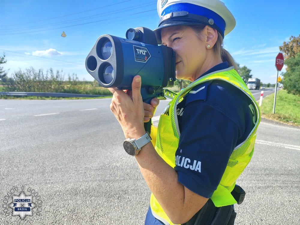 policjantka w białej czapce i odblaskowej kamizelce mierzy prędkość