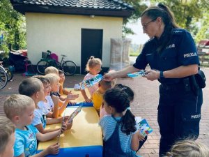 POLICJANTKA ROZDAJE DZIECIOM KSIĄŻECZKI