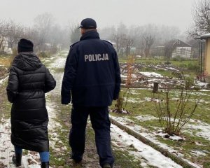 umundurowany policjant i pracownica ośrodka pomocy społecznej idą na alejce ogródków działkowych