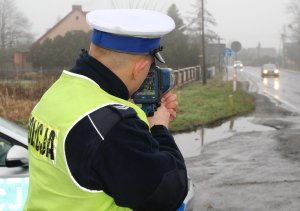 umundurowany policjant mierzy prędkość na ręcznym mierniku prędkości