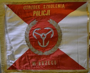 sztandar Ośrodka Szkolenia Policji w Brzegu, w barwach czerwono kremowych, na środku dawny herb miasta Brzeg