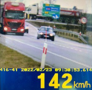 wyświetlacz ręcznego miernika prędkości jadącego pojazdu wskazujący pomiar 142 km/h.