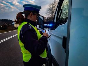 umundurowana policjantka podczas kontroli drogowej legitymuje kierowcę
