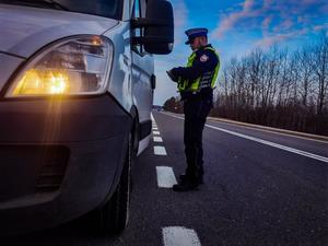 umundurowany policjant podczas kontroli drogowej legitymuje kierowcę