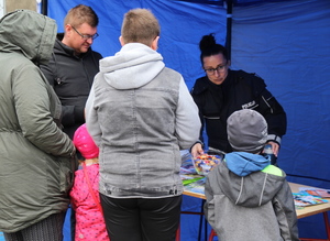 policjantka przekazuje uczestnikom festynu materiały promocyjne