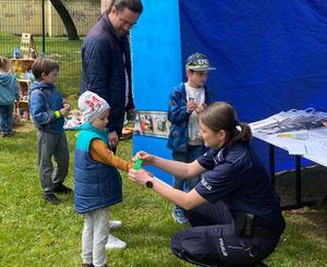 policjantka rozmawia z dzieckiem, przekazuje materiały profilaktyczne