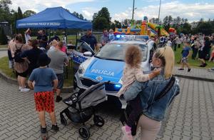 uczestnicy pikniku - dzieci i dorośli, policjanci, radiowóz, niebieski namiot