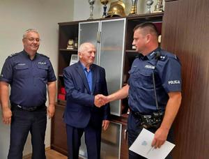 mężczyzna w garniturze i umundurowani policjanci podczas wręczania rozkazu personalnego