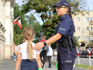 umundurowana policjantka przekazuje dziecku opaskę odblaskową