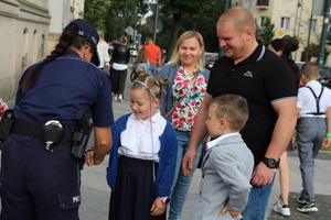 umundurowana policjantka przekazuje dziecku opaskę odblaskową