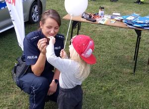 Umundurowani policjanci podczas Opolskich Dni rodziny przekazują dzieciom materiały promocyjne