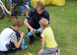 policjantka składa z dziećmi modele radiowozów