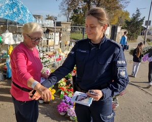 policjantka rozmawia z seniorami i przekazuje im ulotki i elementy odblaskowe