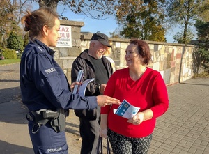 policjantka rozmawia z seniorami i przekazuje im ulotki i elementy odblaskowe