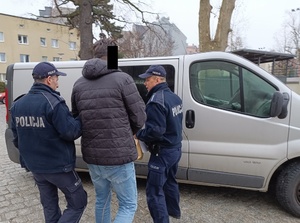 umundurowani policjanci prowadzą zatrzymanego mężczyznę