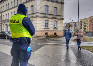 umundurowany policjant patroluje miasto w rejonie przejścia dla pieszych