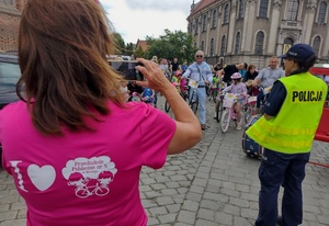 policjantka, kobieta w różowej bluzce robi zdjęcie zebranym osobom