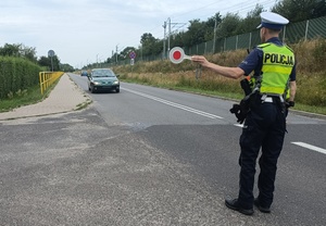 policjant w żółtej kamizelce zatrzymuje samochód do kontroli