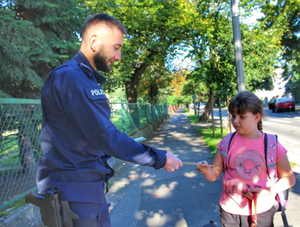 policjant przekazuje dziewczynce odblask