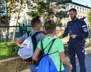 policjant przekazuje chłopakom odblaski