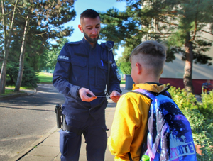 policjant przekazuje uczniowi odblask