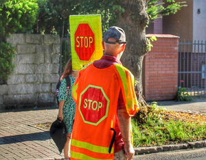 mężczyzna w odblaskowej kamizelce i znakiem stop