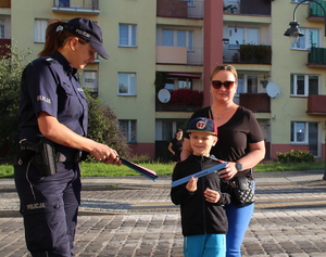 policjantka w mundurze daje odblask chłopcu