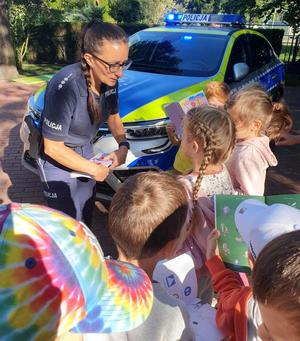 policjantka rozdaje dzieciom książeczki