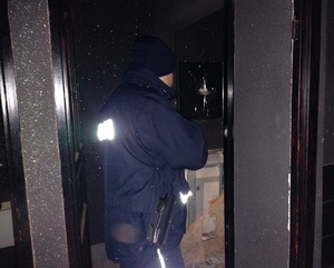 policjant świeci latarką w opuszczonym budynku