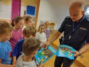 policjant przekazuje dzieciom książeczki