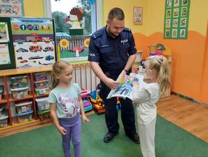 dziewczynki wręczają policjantowi rysunki