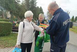 policjant przekazuje seniorom elementy odblaskowe