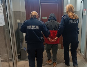 umundurowane policjantki prowadzą zatrzymanego z kajdankami na rękach