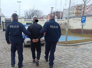 umundurowani policjanci prowadzą zatrzymanego