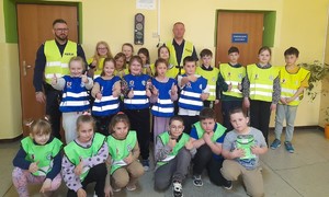 policjanci i grupa dzieci w kamizelkach odblaskowych