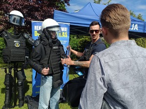policjant pokazuje młodzieży sprzęt przeciwuderzeniowy