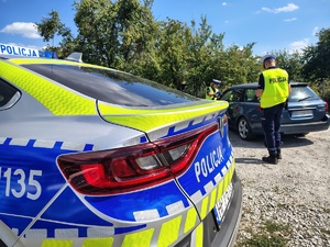 radiowóz, w tle policjanci kontrolują pojazd