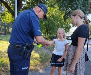 policjant przekazuje odblask dziewczynce
