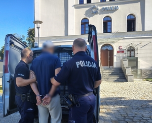 policjanci prowadzą poszukiwanego do radiowozu