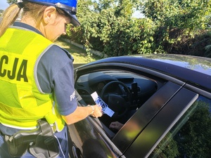 policjantka przekazuje kierowcy ulotki